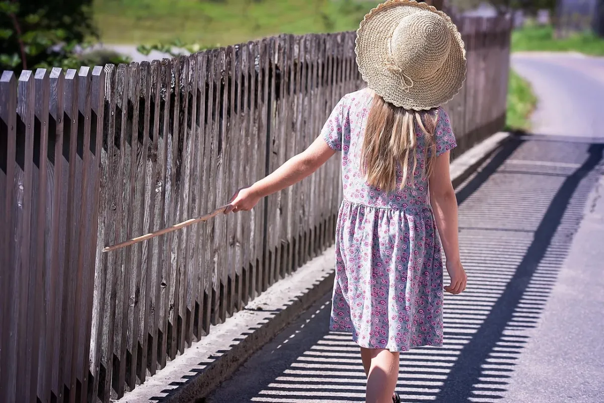Dziewczynka w letniej sukience spaceruje wśród zieleni, ciesząc się słonecznym dniem na łonie natury.